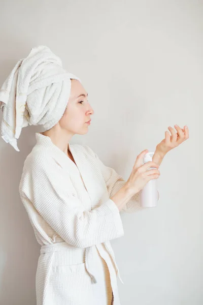 Mulher europeia em toalha e roupão de banho segurando loção corporal — Fotografia de Stock