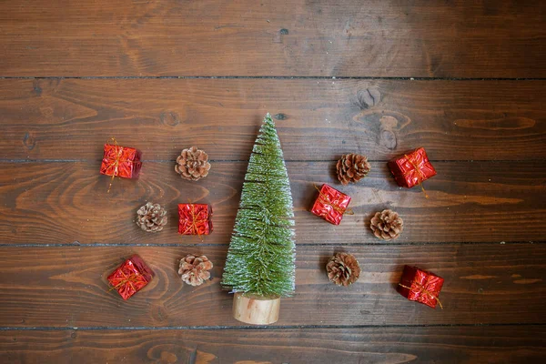 Pequena árvore de Natal, presentes vermelhos e cones no fundo de madeira escura — Fotografia de Stock