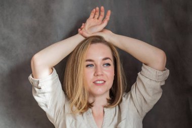 Gülümseyen güzel sarışın Avrupalı kadın Elleri başının yanında