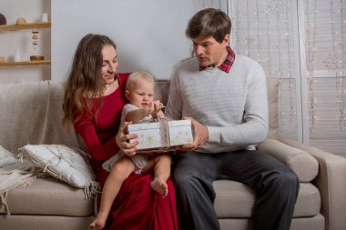  Aile kanepede hediyelerle oturuyor. Baba, anne ve bebek