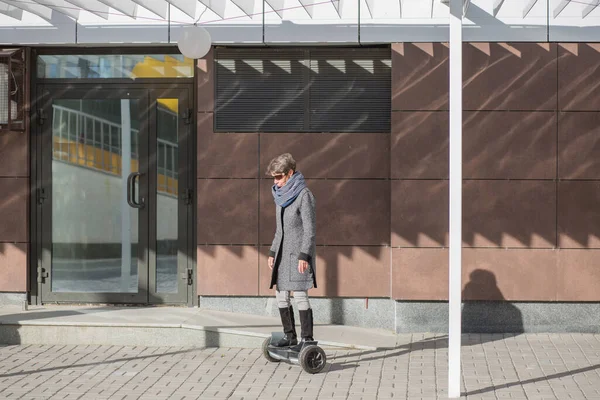 Fashion senior woman on gyroscooter in the city. Autumn. — Stock Photo, Image