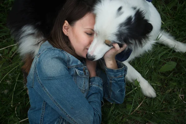 Australian shepherd lying on the grass with Woman face to face — Stock Photo, Image