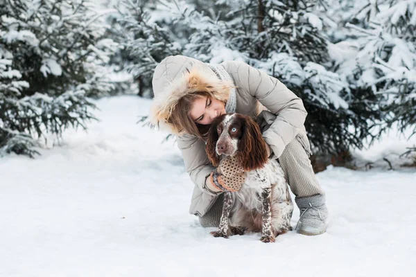 Donna felice che si abbraccia con il cioccolato spaniel nella foresta invernale. vicino. — Foto Stock