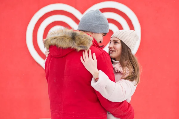 Pareja joven abrazándose en la ciudad cerca de un gran corazón en la pared. San Valentín — Foto de Stock