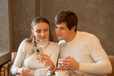 Kafede kahve içen genç bir çift. İnternetten alışveriş. 