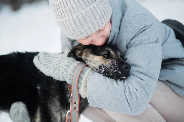 Mulher segurando cão rafeiro com amor na floresta de inverno. Fechar — Fotografia de Stock