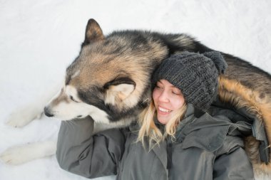 Alaska Malamute 'unu kucaklayan gülümseyen bir kadın. Kapat..