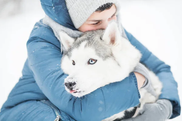 Mulher abraçando Snowy siberian husky no inverno. Retrato de perto. Cão. — Fotografia de Stock