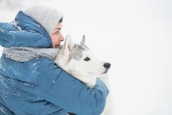 Femme embrassant husky sibérien enneigé en hiver. portrait rapproché. Chien. — Photo