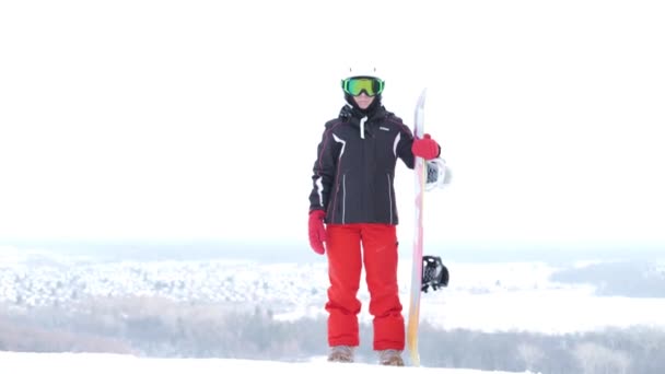 Senior Caucasian woman in sports wear with snowboard standing in the mountains. — Stock Video