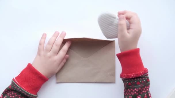 Kinderen handen leggen weefsel hart in ambachtelijke envelop. Milieuvriendelijke Valentijnsdag — Stockvideo