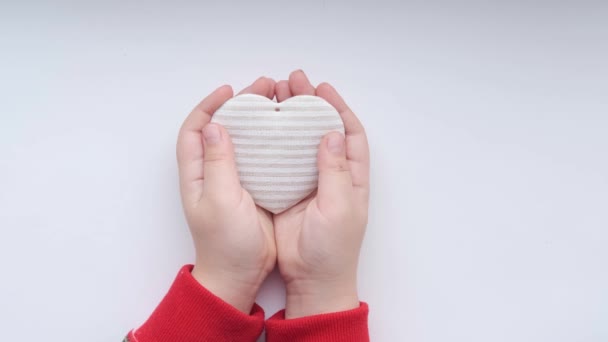 Barnens händer håller i vävnadshjärtat. Miljövänlig Alla hjärtans dag — Stockvideo