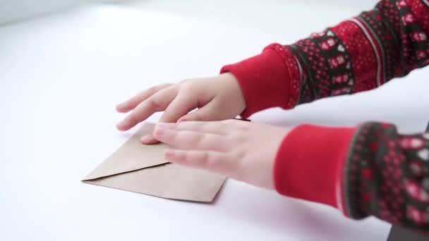 Le mani dei bambini disegnano il cuore sulla busta artigianale con il cuore di carta rossa. San Valentino — Video Stock