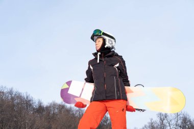 Kırmızı ve siyah spor giyen yaşlı kadın snowboard 'lu.