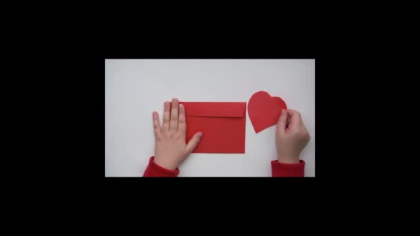 Kids hands put red paper heart in red envelope. valentine day Stock Video