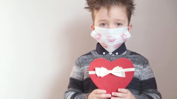 Cute little boy w muszce z pudełka prezentów serca i maski twarzy Walentynki. — Wideo stockowe