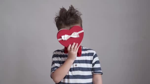 Aranyos fiú tánc piros-fehér szív ajándék doboz. Valentin-nap. — Stock videók