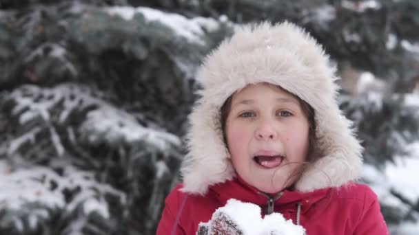 Pouco bonito menina caucasiana feliz no chapéu de inverno brincando com a neve. Comer neve. — Vídeo de Stock