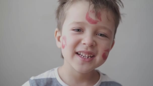 Netter kleiner Junge mit vielen Lippenstiftküssen im Gesicht singen Valentinstag. Nahaufnahme. — Stockvideo
