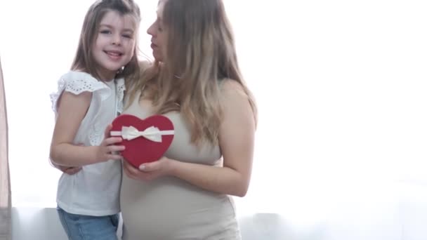 Ragazzina caucasica con la madre bionda incinta fa un regalo al cuore. San Valentino. — Video Stock