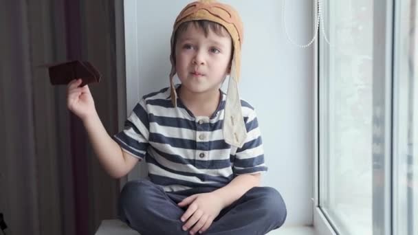 Niño piloto serio preescolar en casco jugando con avión de papel. Viaje de ensueño — Vídeo de stock