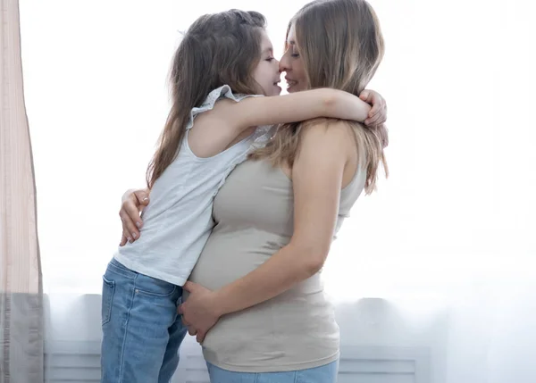 Caucasian happy preschool girl hugs with blonde pregnant mother. Happy family. — Stock Photo, Image