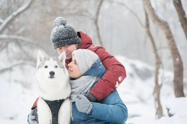 Pareja abrazándose con perro husky en invierno. San Valentín. —  Fotos de Stock