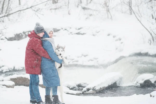 Abraço casal com cão husky siberiano em winter.waterfall. Dia dos namorados. — Fotografia de Stock