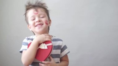  Yüzünde bir sürü ruj izi olan mutlu bir çocuk ve kalp hediye kutusu olan sevgililer günü.. 