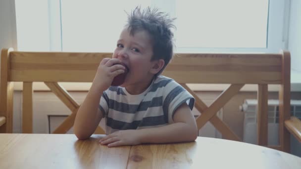 Um menino caucasiano a comer maçã vermelha. Aproveita. Fechar. — Vídeo de Stock