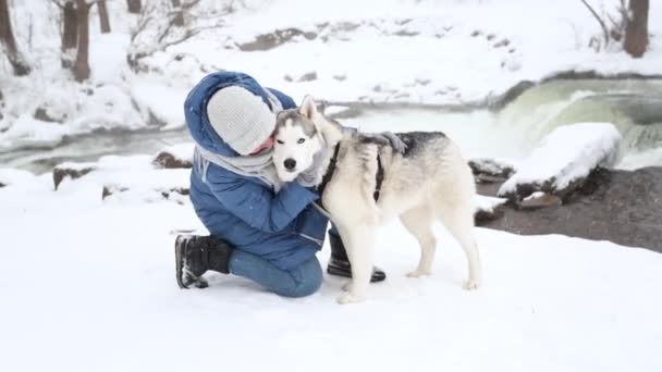 Kavkazská žena objímající sibiřský husky psí sníh v zimě. Řeka břehu. — Stock video