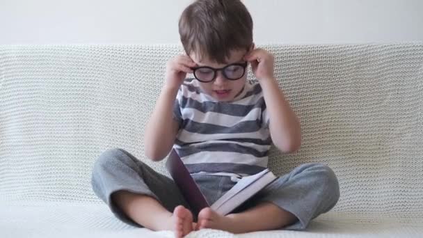 Vorschulkind mit Brille sitzt und lernt lesen — Stockvideo