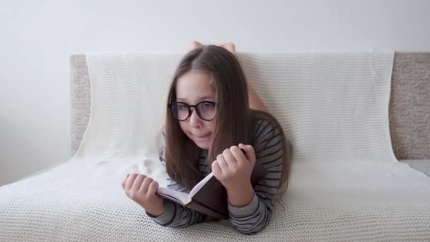 4k. pequeña linda chica caucásica en gafas libro de lectura — Vídeos de Stock