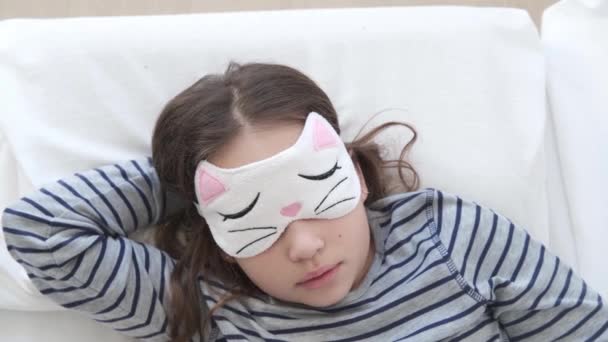 4k. Dormir linda niña de la escuela primaria con máscara para los ojos. Vista superior — Vídeos de Stock