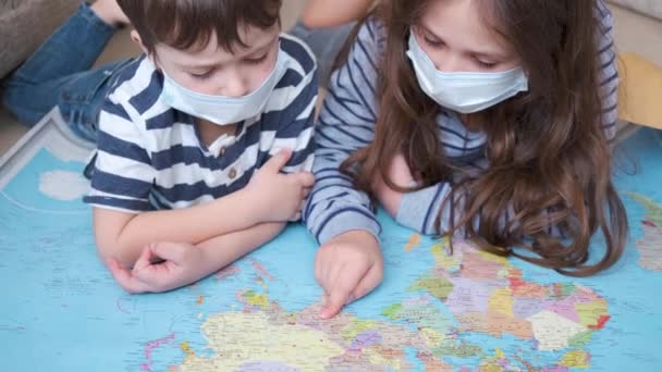 4K. Duas crianças em máscara protetora com mapa — Vídeo de Stock