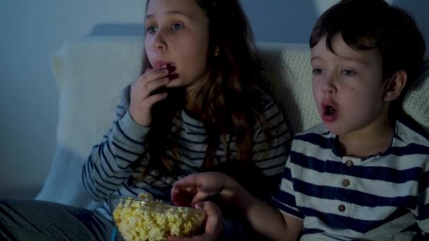 4k. petit mignon caucasien fille et garçon regarder des films et manger pop-corn — Video