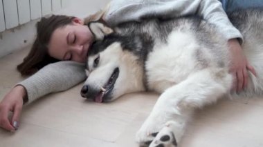4 bin. Alaska 'lı genç köpeğiyle yerde yatan beyaz bir kadın var. Kapalı.