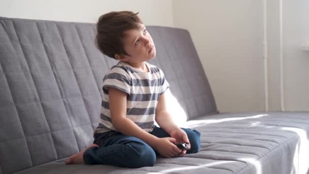 4k. Petite mignonne sortie garçon caucasien regarder la télévision sur le canapé — Video
