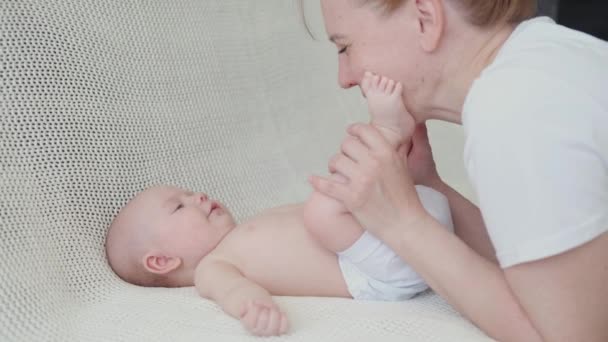 4k. mãe feliz brincar com o bebê pequeno. beijar as mãos e pés — Vídeo de Stock