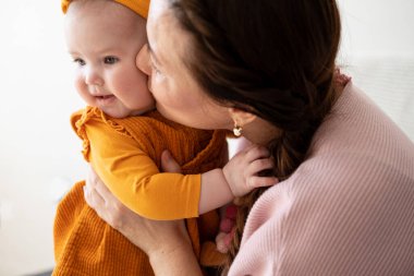 Anne kucağında küçük bir çocuk öpücükle evde eğleniyor.