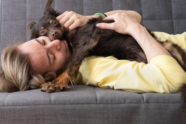 快乐的金发女人躺着睡觉有趣的棕色俄罗斯玩具小狗 — 图库照片