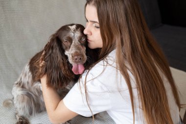 Çekici sarışın kadın Rus spanyel köpeğini farklı renklerde öpüyor. Otur. 