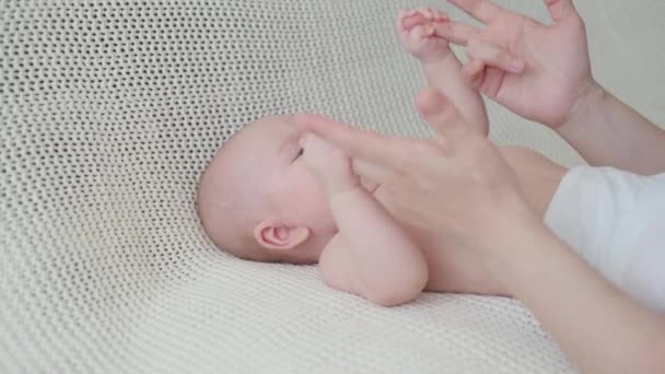 4k. little baby boy lying on white plaid play with mothers hands. Happy family — Stock Video