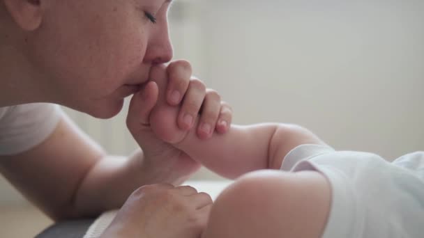 4k. Atractiva madre feliz beso olfatear niños pequeños dedos de los pies. Familia feliz — Vídeos de Stock