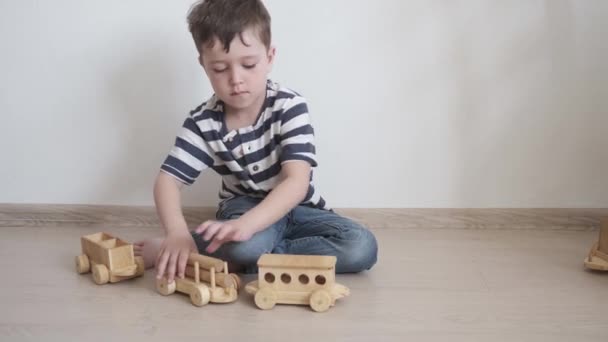 4k. Menino brincando com trem de madeira. brinquedos ecológicos — Vídeo de Stock