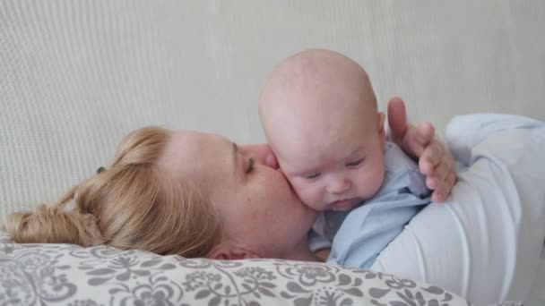 4k 。快乐的母亲把小宝宝抱在肚子里亲吻着躺在床上. — 图库视频影像