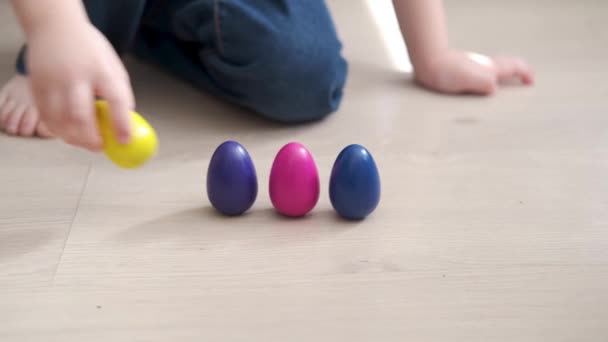 4kだ。可愛い白人の男の子は色のついた卵で遊ぶ。イースター — ストック動画