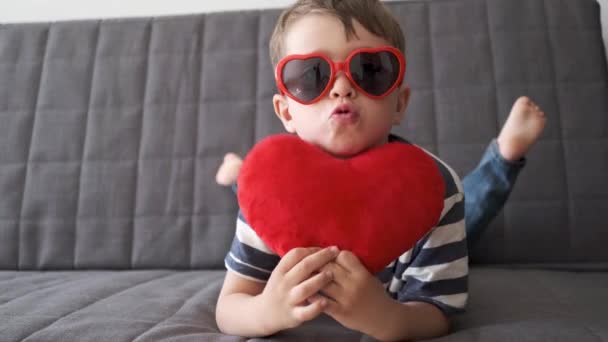 4k. Engraçado menino bonito em óculos de sol coração com grande coração. Dia dos namorados. — Vídeo de Stock