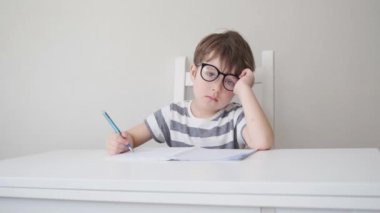 4k. little cute serious caucasian boy in glasses study, write