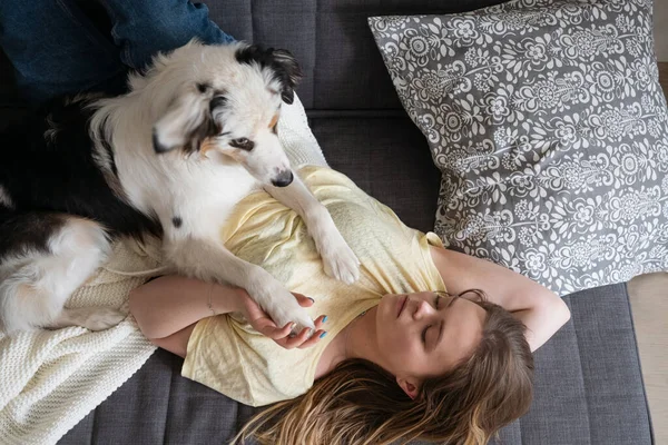 Attractive woman lying with blue merle Australian shepherd dog — Stock Photo, Image